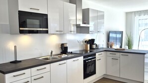 A modern kitchen with white cabinetry, a black countertop, and stainless steel appliances. - Spacious Winterberg Stay for 7 Guests (Winterberg)