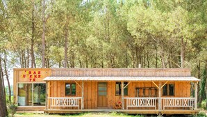 A wooden cabin with a porch, a visible entrance, and a signboard.