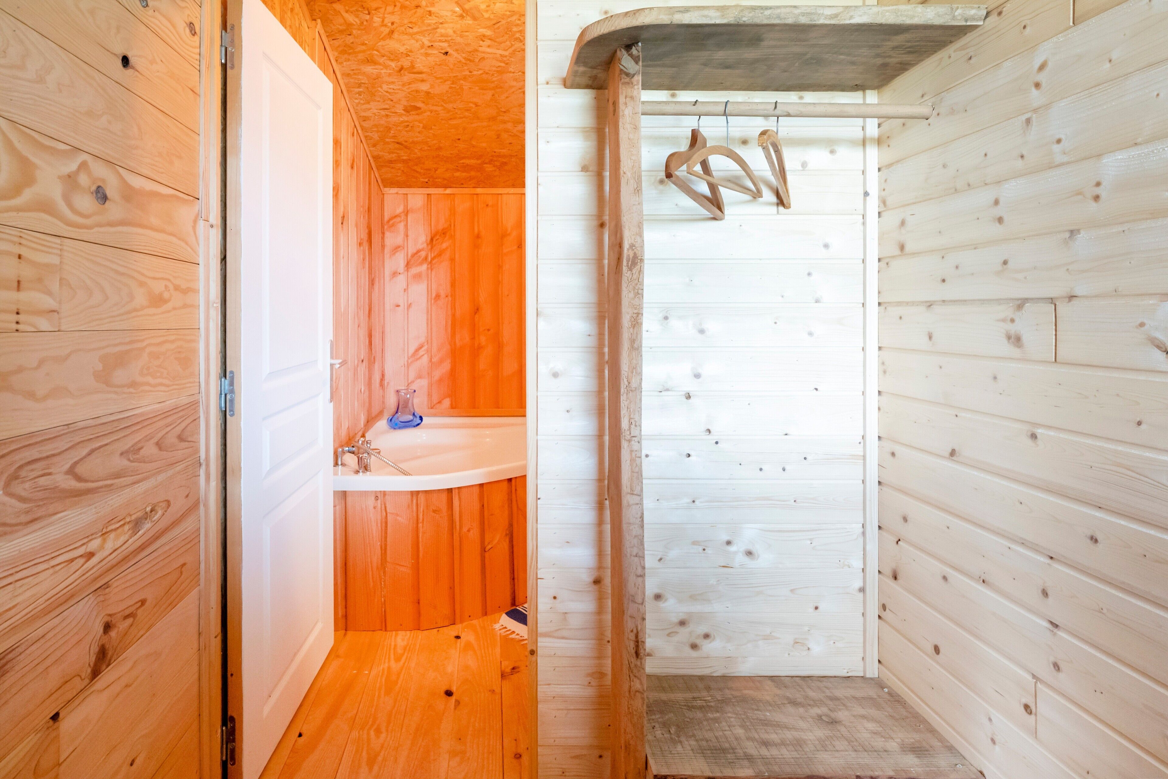 Een houten hut met een badkamer, inclusief een wastafel en douche.