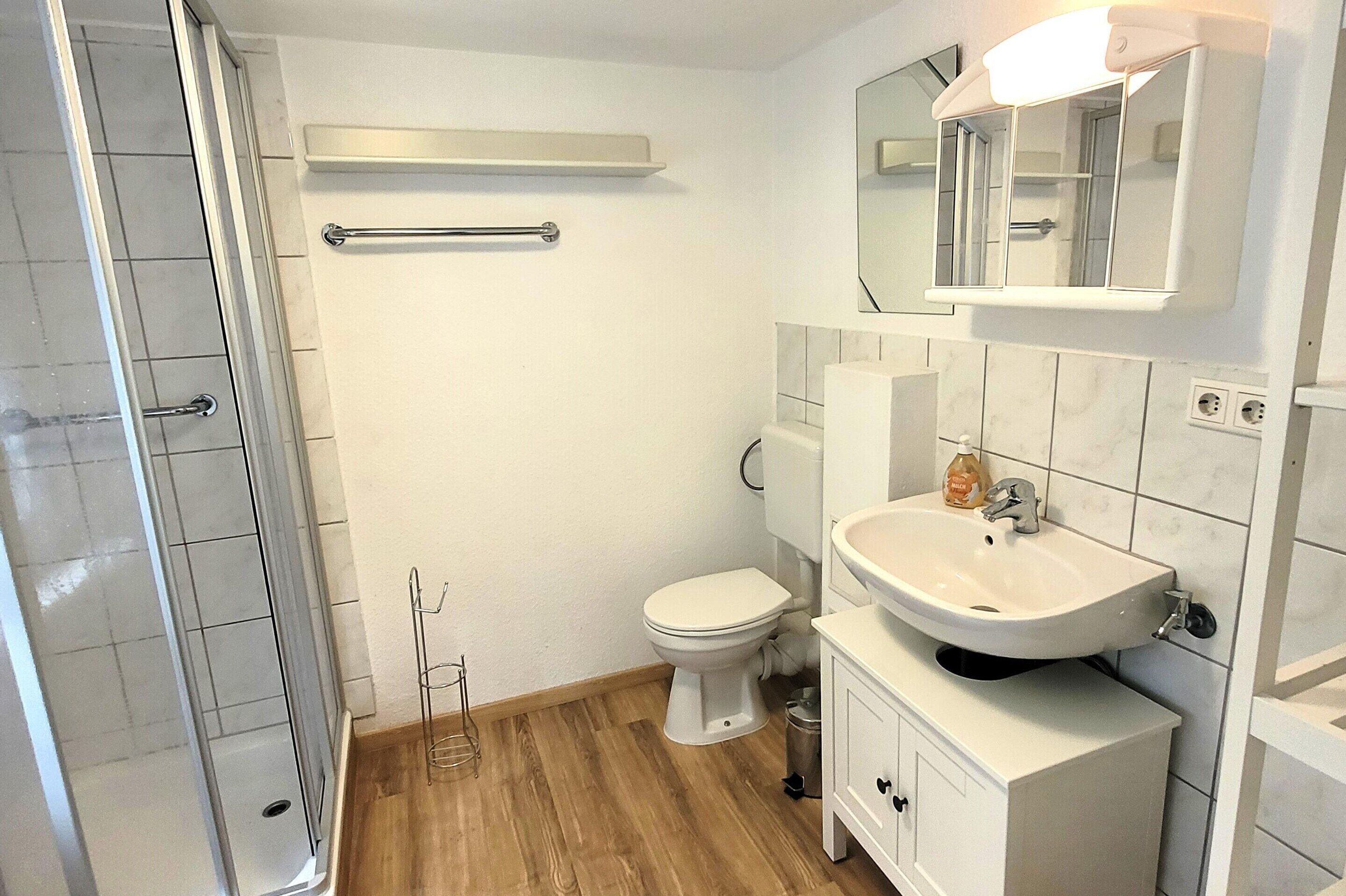Une salle de bain avec douche, toilettes et lavabo.