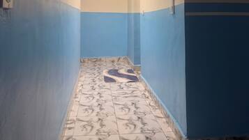 A narrow hallway with patterned floor tiles, walls painted in two-tone blue and beige, and a ceiling light.