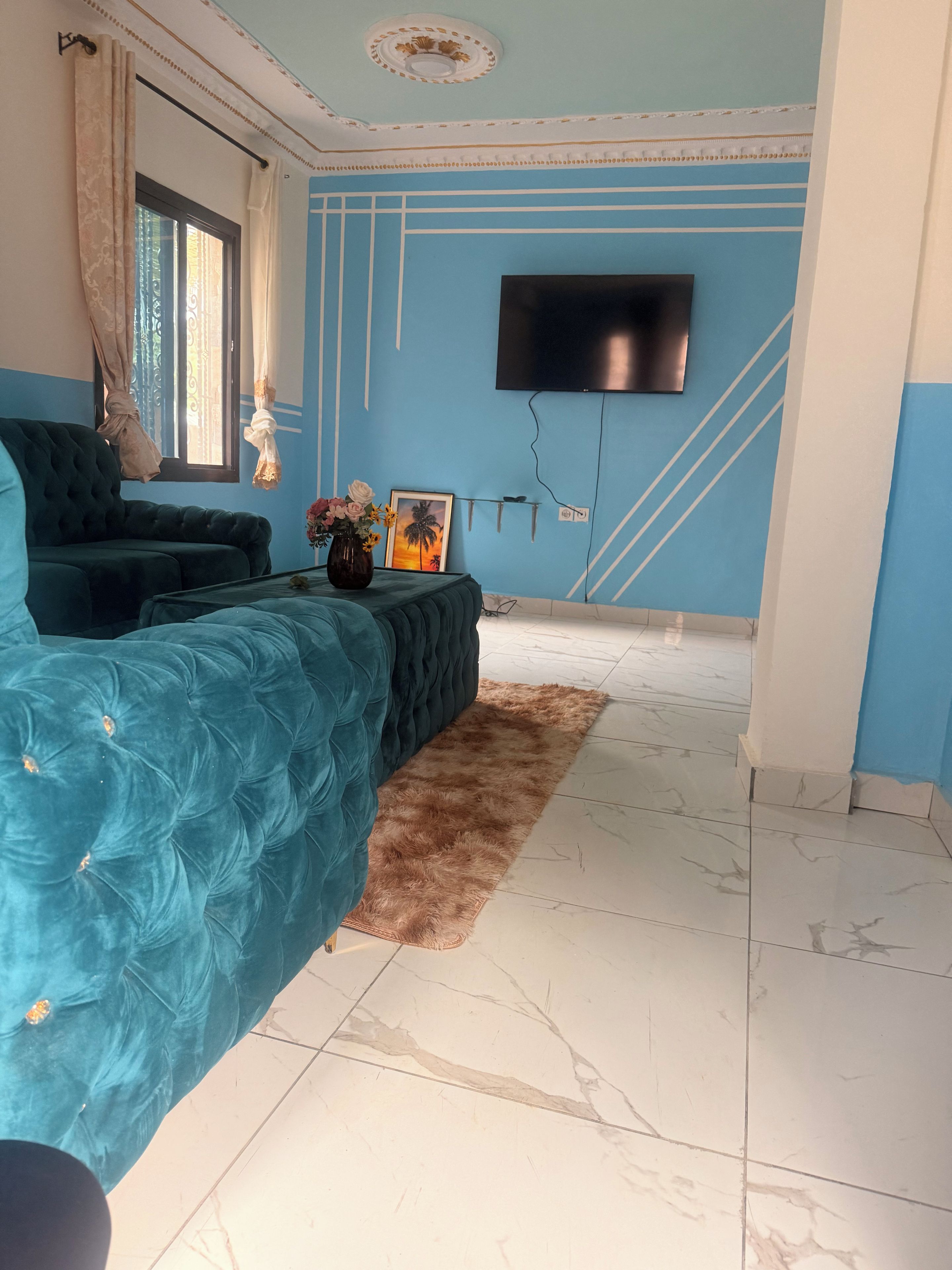 A room with a large bed, a flat-screen TV mounted on the wall, and a window with curtains.