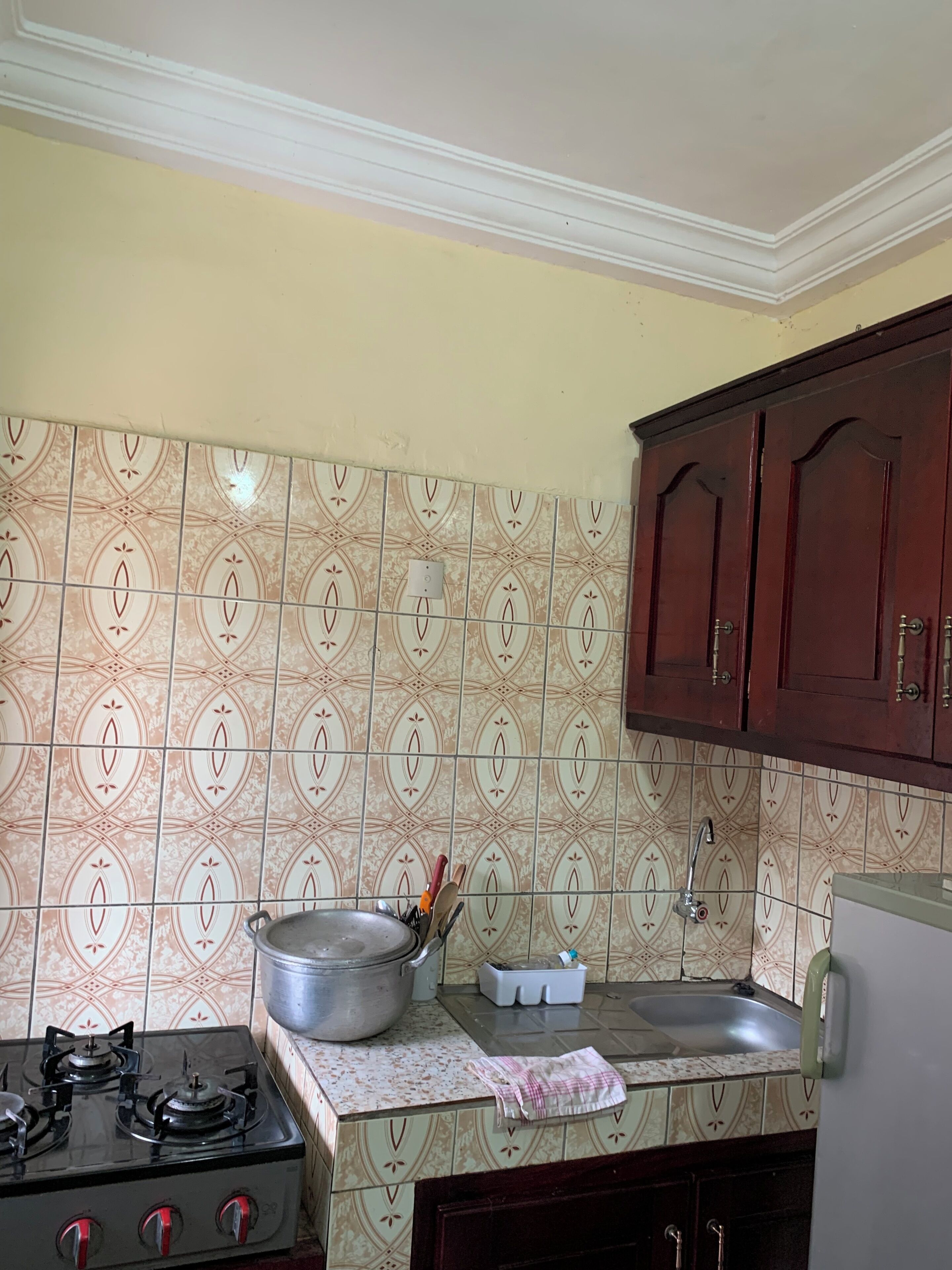 A kitchen with patterned tiles, a gas stove, a sink, and wooden cabinets.