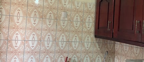 Une cuisine avec des carreaux décoratifs, une cuisinière à gaz, un évier et des armoires en bois.