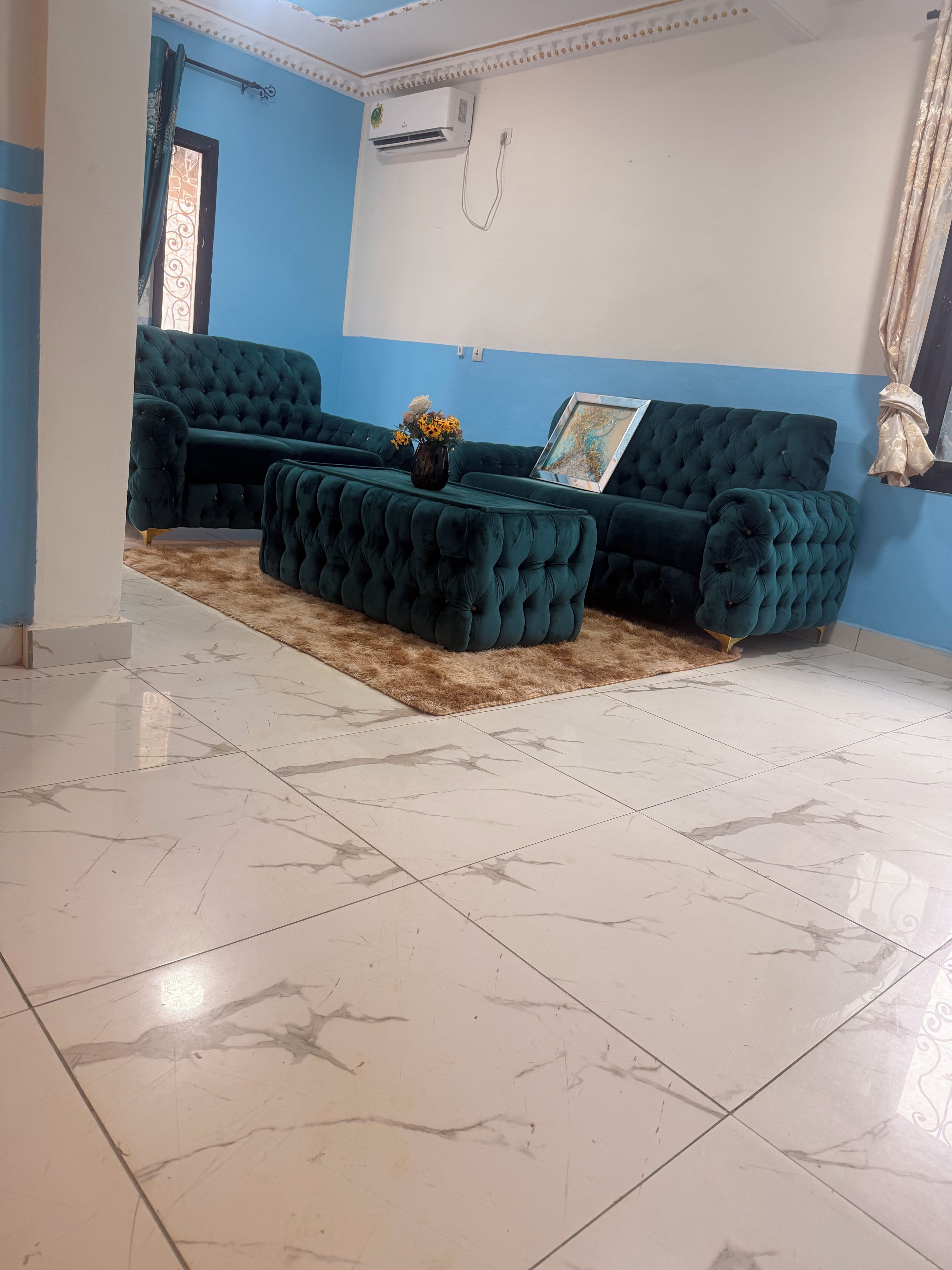Una sala de estar con una decoración en tonos azul y blanco, que incluye un sofá modular, una mesa de centro y una alfombra estampada.