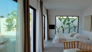 A modern hotel room with a large bed, a wooden chair, and a view of the outdoors through large windows. - EBLI'7. HOTEL BOUTIQUE (Orihuela)