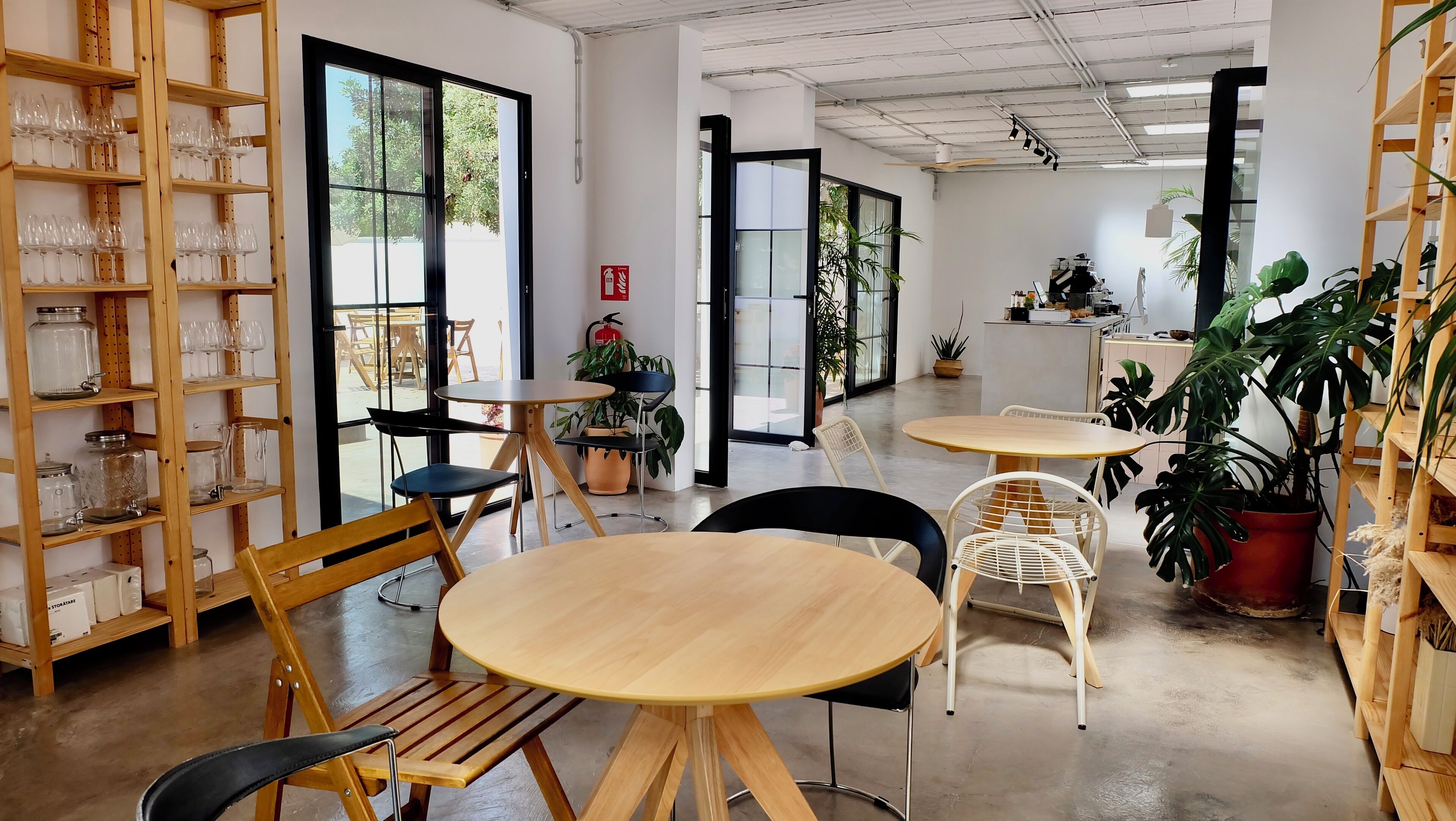 A modern interior with wooden furniture, glassware on shelves, and potted plants.