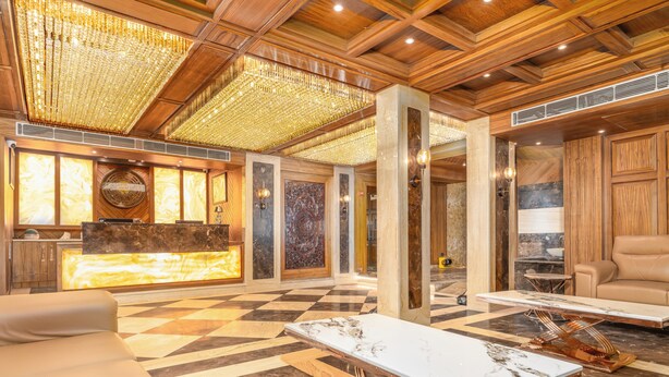 A lobby with a checkered floor, a reception desk, a sofa, a coffee table, and a chandelier. - Hotel Central Park (Srinagar)
