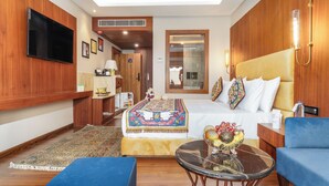 A modern hotel room with a large bed, a television, a desk, and a seating area. - Hotel Central Park (Srinagar)
