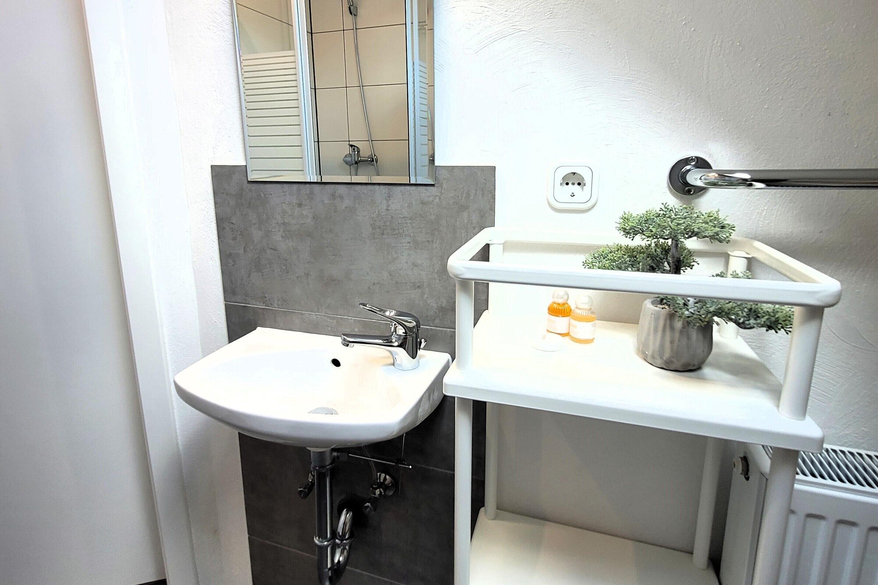 A bathroom with a white sink, a mirror, and a towel rack.