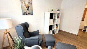 A modern living room with grey sofas, a white side table, a floor lamp, and a bookshelf. - Apartment in Winterberg Near Ski Lift (Winterberg)