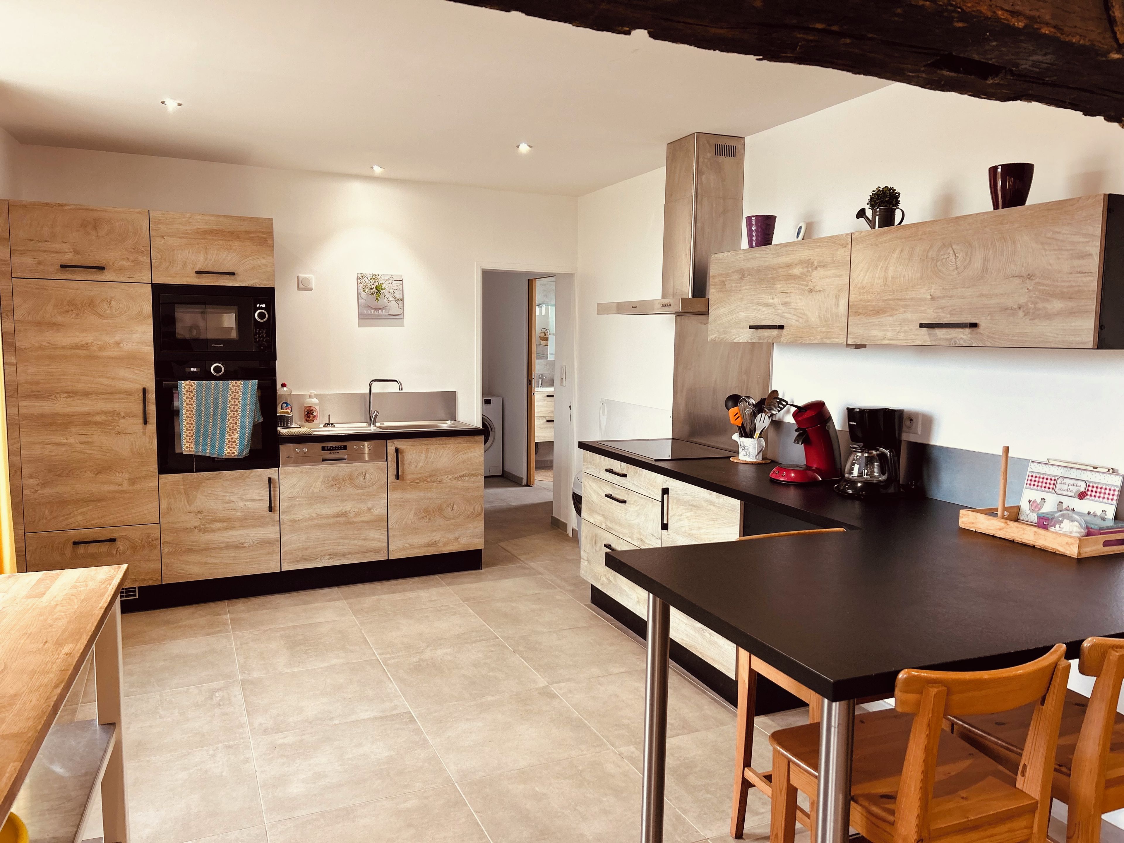 Eine moderne Küche mit Holzschränken, einer schwarzen Arbeitsplatte und einem Essbereich mit einem Holztisch und Stühlen.
