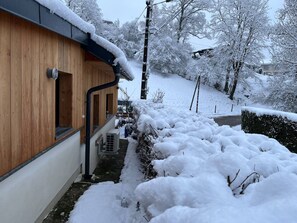 Un bâtiment en bois doté d’une entrée abritée et d’un chemin recouvert de neige.