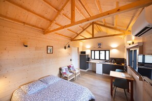 Une cabane confortable avec un intérieur en bois, un lit, un bureau et une petite cuisine.