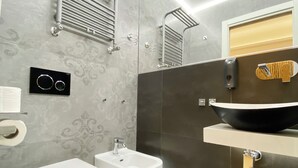 A modern bathroom with a bidet, toilet, vanity with a sink, and a towel rack. - Casa Granatelli (Palermo)
