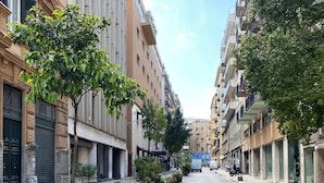 A street lined with trees and buildings, with a clear sky above. - Casa Granatelli (Palermo)