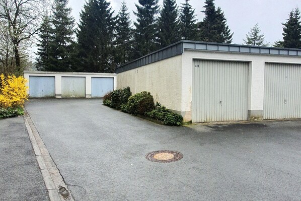 A building with three large grey doors, a paved driveway, and a manhole cover. - Apartment in Winterberg Near Kappe Mountain (Winterberg)