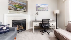 Een woonkamer met een open haard, een bureau en een bank.