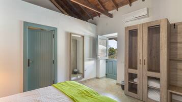 A bedroom with a bed, a green towel, a wardrobe, and an air conditioning unit.
