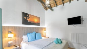 A bedroom with a bed, a painting of a sunset, a television, and a nightstand with a lamp. - 'Casa Mica' with Mountain View, Wi-Fi and Air Conditioning (Vega de San Mateo)