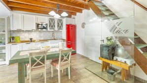 A kitchen with white cabinets, a red refrigerator, a wooden dining table, and a glass partition with 'Mica' written on it. - 'Casa Mica' with Mountain View, Wi-Fi and Air Conditioning (Vega de San Mateo)