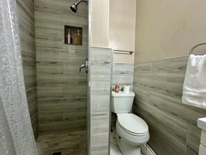 Ein Badezimmer mit Dusche, Toilette und einer kleinen Ablage für Toilettenartikel.