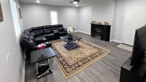 A living room with a black leather sofa, a coffee table, a TV, and a fireplace. - Cozy Upper-Level Retreat (Waukegan)