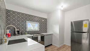 A modern kitchen with a stainless steel refrigerator, a gas stove, and a patterned backsplash. - Cozy Flat Two Sleeping Areas Full-size bed (Ceiba)