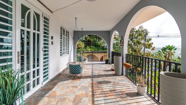 A covered balcony with a tiled floor, white-framed windows, and potted plants. - Cozy Flat Two Sleeping Areas Full-size bed (Ceiba)