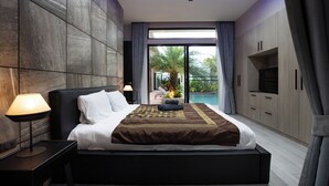 Un dormitori modern amb un llit gran, un ventilador de sostre i vista a una piscina.