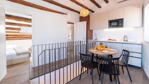 A modern kitchen with white cabinets, a microwave, and a dining area with a table and chairs. - Seagull's View - Breezy 1 Bedroom with Seaview in the Heart of Rovinj's Old Town (Rovinj)