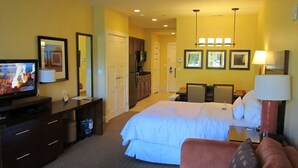 Une chambre d’hôtel comprenant un lit, un bureau avec une télévision, une kitchenette et une salle de bain.