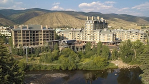 Un complexe hôtelier composé de plusieurs bâtiments, avec une rivière au premier plan et des montagnes en arrière-plan.