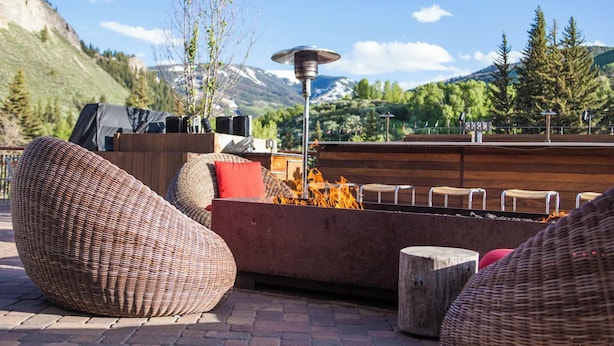 Une terrasse dotée de meubles en osier, d’un foyer extérieur et offrant une vue sur les montagnes.
