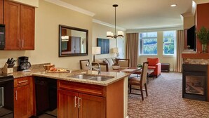 Une chambre d’hôtel équipée d’un coin cuisine, d’une table à manger, d’un canapé et d’une cheminée.