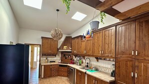 A kitchen with wooden cabinets, a black refrigerator, and a hanging plant. - Rustic Villa with Private Pool near Ocean, Hiking & Cycling Trails – Sleeps 9 (CN)