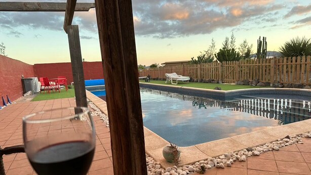 A swimming pool with a wooden deck, a glass of red wine, and a view of the backyard. - Rustic Villa with Private Pool near Ocean, Hiking & Cycling Trails – Sleeps 9 (CN)