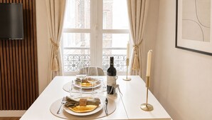 A dining table set with plates, cutlery, a bottle of wine, and candles.