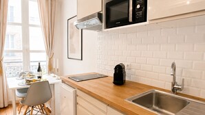 Una cocina moderna con encimera de madera, pileta de acero inoxidable y microondas.