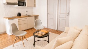 Un espacio habitable compacto con kitchenette, dos sillas, un sofá y una pequeña mesa.
