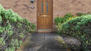A brick building with a wooden double door, a small overhang above the door, and a light fixture to the left.