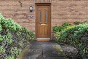 A brick building with a wooden double door, a small overhang above the door, and a light fixture to the left.