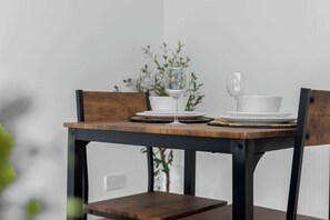 A dining table with chairs, a glass, plates, and a bowl.