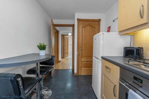 A compact kitchen with a dining area, a refrigerator, a microwave, and a stove.