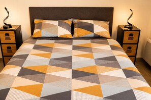 A bed with a geometric patterned bedspread, two matching pillows, and two bedside tables with lamps. - Charming 3 rooms located in Le Cannet, near Cannes (Le Cannet)