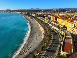 A coastal cityscape with a beach, promenade, and buildings along the waterfront.