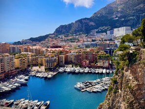 Un puerto deportivo con numerosas embarcaciones amarradas, rodeado de edificios residenciales y un paisaje montañoso.
