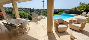 An outdoor patio with a pool, wicker furniture, and a view of the city.