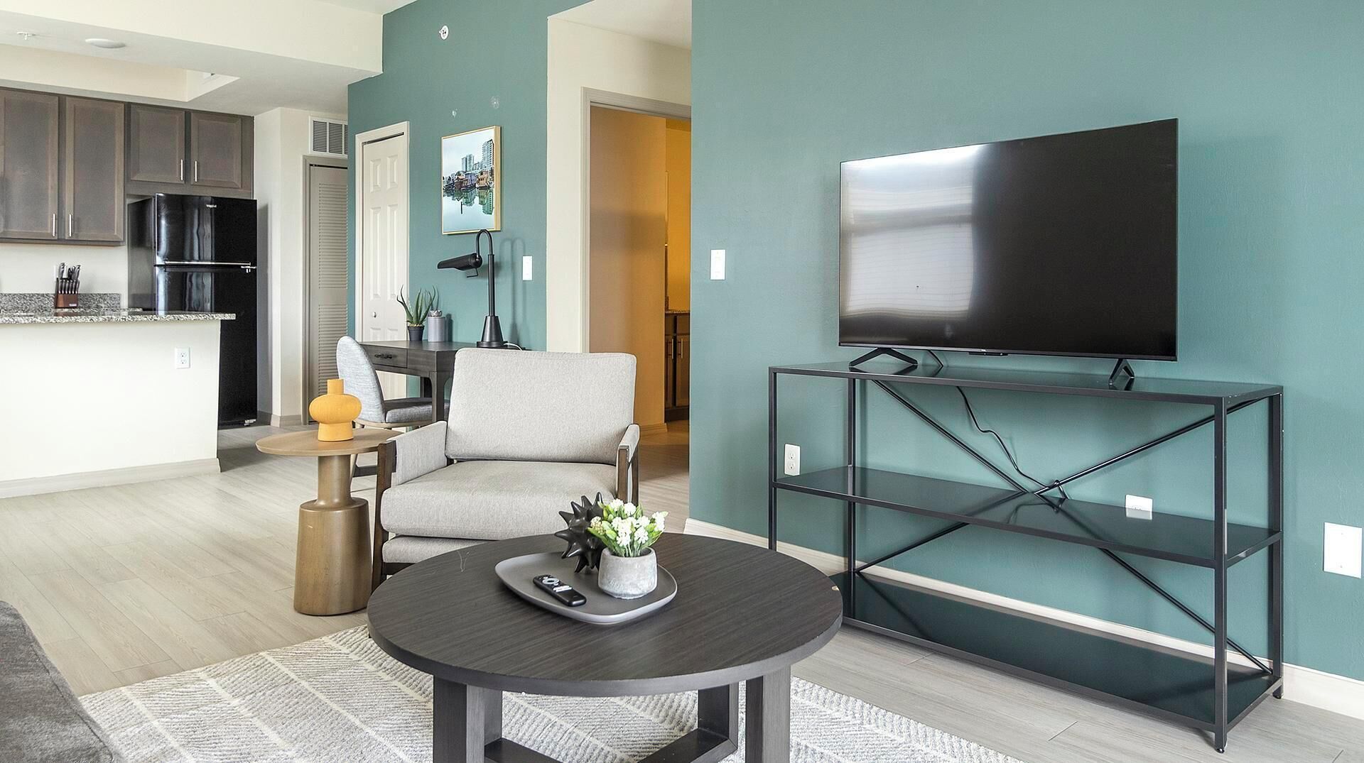 A modern living room with a flat-screen TV, a round coffee table, and a comfortable armchair.