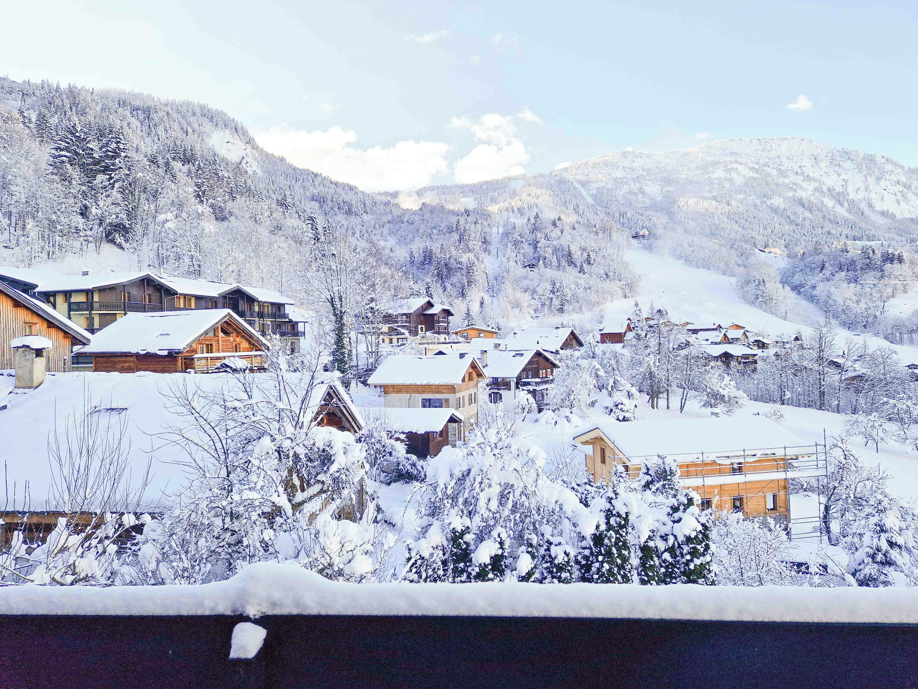 A snow-covered village with wooden houses and a mountain backdrop.